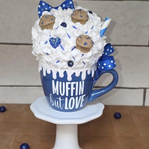 Close-up of hand-placed sprinkles and faux blueberries on handmade fake bake muffin display piece.