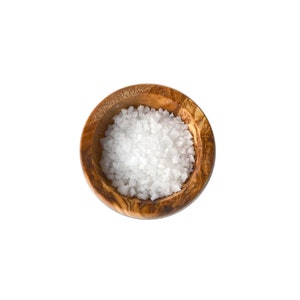 Pode incluir: Uma pequena tigela de madeira cheia de sal marinho branco.