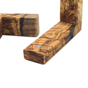 Puede incluir: Dos soportes de esquina de madera de olivo con un patr&oacute;n de veta de madera natural. Los soportes est&aacute;n conectados con una peque&ntilde;a pieza de metal.