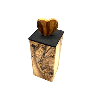 May include: A wooden box with a heart-shaped lid. The box is made of light-colored wood with dark, swirling grain patterns. The lid is a dark gray color, and the heart-shaped top is made of the same wood as the box.