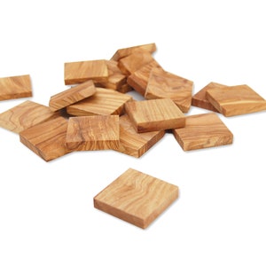 Könnte beinhalten: Ein Haufen quadratischer Holzfliesen aus Olivenholz, auf einem weißen Hintergrund verstreut.