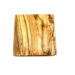 Könnte beinhalten: Ein quadratisches Schneidebrett aus Holz mit natürlicher Holzmaserung. Das Brett hat eine hellbraune Farbe mit dunkleren braunen Streifen.