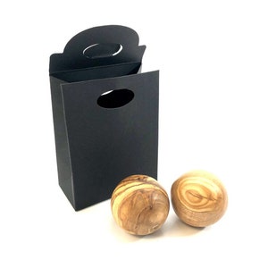 Può includere: Due sfere di legno con un motivo a venature di legno naturale, confezionate in una scatola regalo nera con manico.