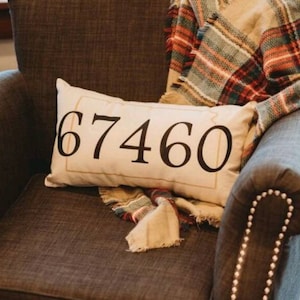 May include: A gray armchair with a plaid throw blanket and a white pillow with the number "67460" printed on it.