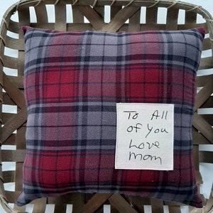 May include: A red and gray plaid pillow with a white tag that says "To All of you love mom".
