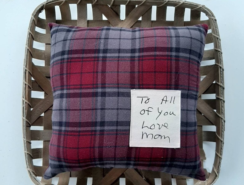 May include: A red and gray plaid pillow with a white tag that says "To All of you love mom".
