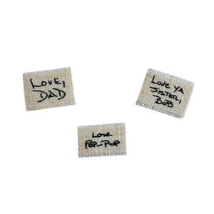 May include: Three small, rectangular beige fabric patches with handwritten black text. One reads "Love, Dad", another "Love Ya Sister, Bob", and the third "Love Pop-Pop".