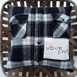 May include: A black and white plaid pillow with a white fabric patch that says "Love Dad". The pillow is in a wooden basket.