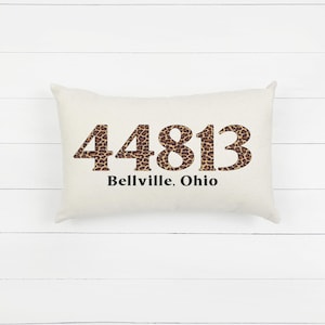 May include: A white cushion with a leopard print design featuring the numbers 44813 and the text "Bellville, Ohio".