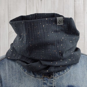 Könnte beinhalten: Ein dunkelgrauer Infinity-Schal mit goldenen Glitzerpunkten. Der Schal ist aus einem weichen, bequemen Stoff gefertigt und perfekt, um sich im Winter warm zu halten.