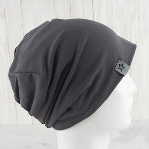 May include: A gray beanie with a small star logo on the side. The beanie is made of a soft, stretchy fabric and has a slouchy fit.