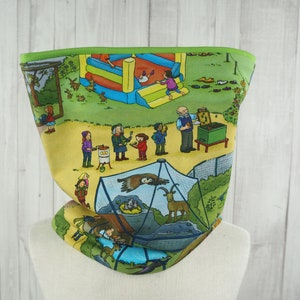 Könnte beinhalten: Ein gelber und grüner Nackentuch mit einer bunten Illustration einer Zooszene. Die Illustration zeigt ein Hüpfburg, einen Imker, ein Vogelgehege und eine Vielzahl von Tieren und Menschen.