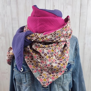 Könnte beinhalten: Ein mehrfarbiger Schal mit rosa und lila Design. Der Schal hat ein Blumenmuster mit rosa, braunen und gelben Kreisen. Der Schal ist um eine Jeansjacke gewickelt.