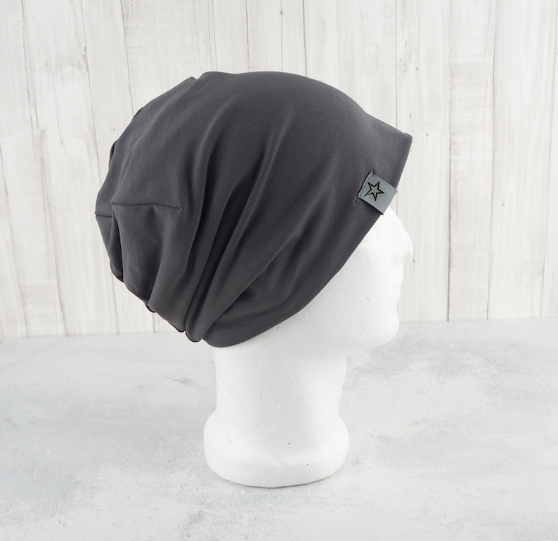 May include: A gray beanie with a small star logo on the side. The beanie is made of a soft, stretchy fabric and has a slouchy fit.