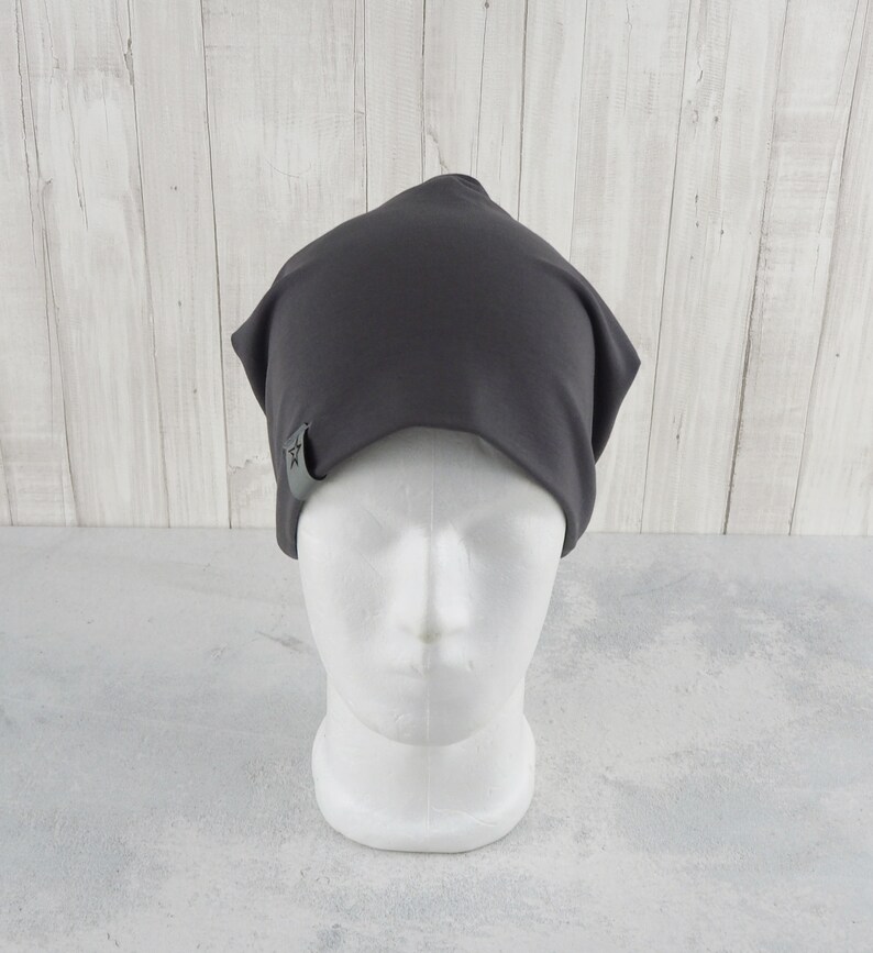May include: A dark gray beanie with a small star logo on the side. The beanie is made of a soft, stretchy fabric and is perfect for keeping your head warm in the winter.