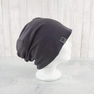 May include: A dark gray beanie with a star logo on the side. The beanie is made of a soft, stretchy fabric and is perfect for keeping your head warm in the winter.