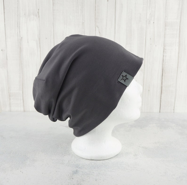May include: A dark gray beanie with a star logo on the side. The beanie is made of a soft, stretchy fabric and is perfect for keeping your head warm in the winter.