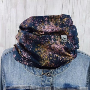 Könnte beinhalten: Ein dunkelblauer Halsschmeichler mit einem rosa und goldenen Spritzmuster. Der Halsschmeichler hat ein kleines weißes Etikett mit einem Stern.