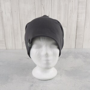 May include: A dark gray beanie with a small gray button on the side.