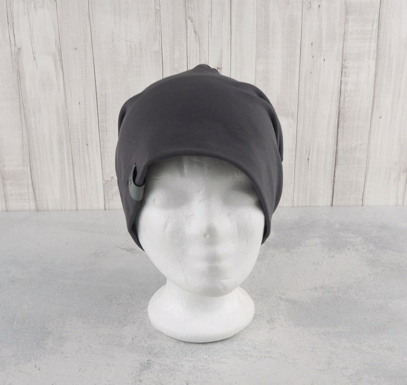 May include: A dark gray beanie with a small gray button on the side.