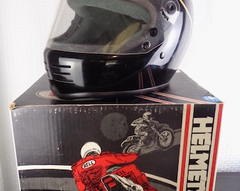 May include: Black motorcycle helmet with a clear visor, gold trim, and the "Bell Helmets" logo. The helmet sits on a box with motorcycle illustrations and the word "HELMETS".