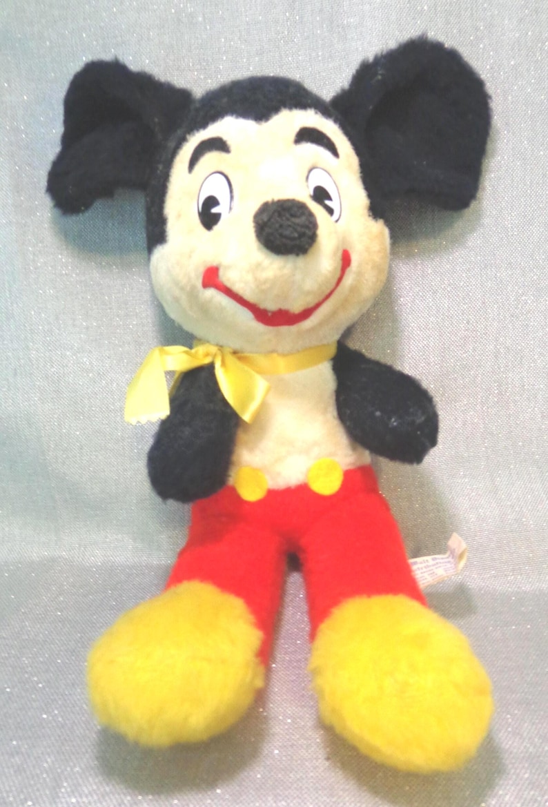 Puede incluir: Un juguete de peluche vintage de Mickey Mouse con orejas negras, un lazo amarillo, pantalones rojos y zapatos amarillos.