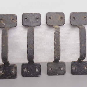 May include: Six black metal door handles with a rectangular shape and a curved handle. The handles have two holes for mounting.