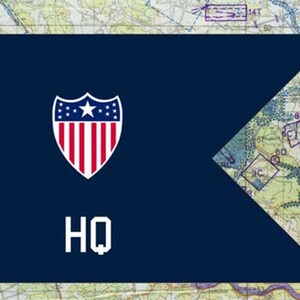 May include: A navy blue flag with a white and red shield emblem featuring a star and stripes, and the letters "HQ" in white. The background is a map.