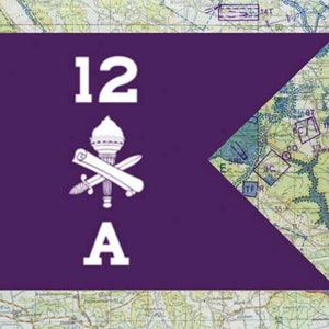 May include: A purple flag with white text and symbols. The flag has the number "12", a torch and crossed sword, and the letter "A". The background is a map.