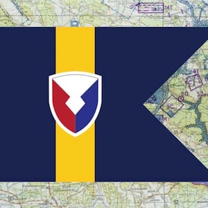 May include: A navy blue flag with a yellow vertical stripe and a white, red, and blue emblem. The flag has a map background. The flag's design is a shield shape with a white top and red and blue bottom.
