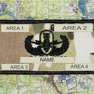 May include: A rectangular patch with a camouflage pattern, featuring a black embroidered emblem and the word "NAME" in a white rectangle. The patch has four areas labeled "AREA 1" through "AREA 4". The background is a map.
