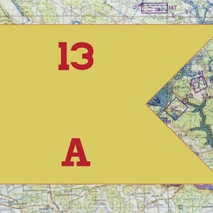 May include: A yellow flag with a red border and the numbers "13" and the letter "A" in red. The flag is set against a detailed map background, with various symbols and lines.