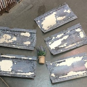May include: Five antique tin ceiling tiles with a distressed white paint finish and blue accents. The tiles have a decorative border and are perfect for adding a vintage touch to any room.