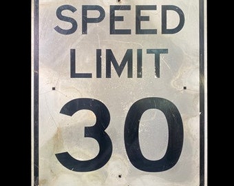 Peut inclure: Un panneau de limitation de vitesse en métal blanc avec du texte et des chiffres noirs. Le panneau indique "SPEED LIMIT 30".