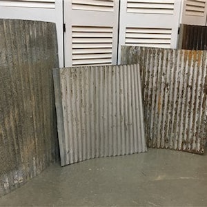 May include: A collection of weathered, corrugated metal sheets in varying sizes and shades of gray and brown. The sheets have vertical ridges and show signs of age and rust, suggesting a vintage or industrial aesthetic.