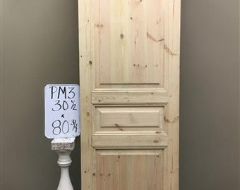 Puede incluir: Una puerta de madera clara con un diseño de paneles elevados. La puerta mide 77,5 cm de ancho y 204 cm de alto.