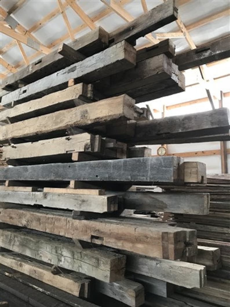Puede incluir: Una pila de vigas de madera recuperada, algunas con nudos e imperfecciones visibles, listas para usar en una variedad de proyectos.