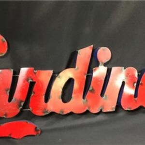 May include: Red metal sign with the word "Cardinals" in a stylized font. The sign has a distressed look, with a blue outline around the letters.