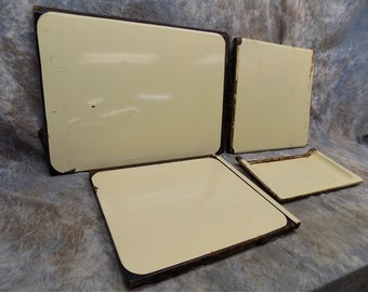 May include: Four off-white enamel stovetop covers with black trim. The covers are rectangular and have a slightly rounded edge.