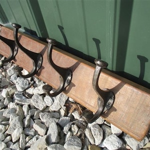 Peut inclure: Un porte-manteau en bois avec cinq crochets en métal noir. Le porte-manteau est fait de bois de récupération et a un aspect rustique.