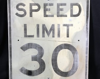 Peut inclure: Un panneau de limitation de vitesse en métal blanc avec du texte et des chiffres noirs. Le panneau indique "SPEED LIMIT 30".