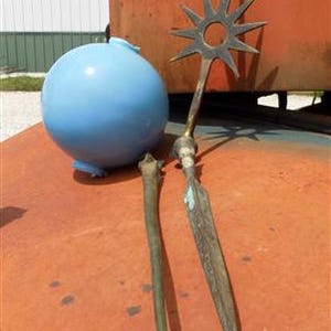 Puede incluir: Un objeto cerámico redondo azul claro con una pequeña boquilla y tres pies, junto a dos piezas decorativas de metal. Una tiene forma de estrella, la otra es un diseño largo, delgado y puntiagudo.
