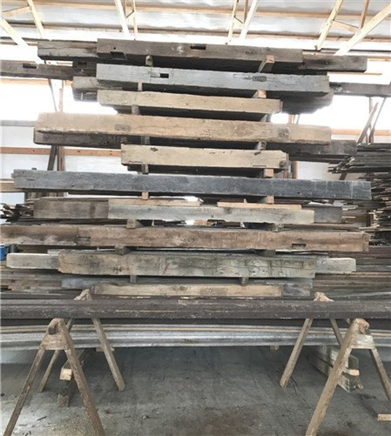Puede incluir: Una pila de vigas de madera recuperada, algunas con agujeros y nudos, listas para usar en un proyecto de bricolaje.