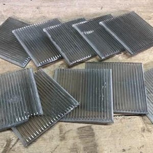 May include: A set of ten clear glass tiles with a ribbed texture. The tiles are square and have a frosted appearance.