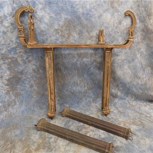 Puede incluir: Soportes de estantería de metal dorado antiguo con detalles de volutas ornamentados. Los soportes están en varias piezas, incluyendo dos soportes verticales y dos piezas horizontales.