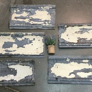 May include: Five antique tin ceiling tiles with a distressed white paint finish and a blue-grey base color. The tiles have a decorative border and are perfect for adding a vintage touch to any room.