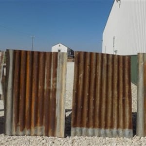 May include: Four rusty corrugated metal sheets, each with a different pattern of rust and wear. The sheets are arranged in a row, with the two on the left slightly overlapping.