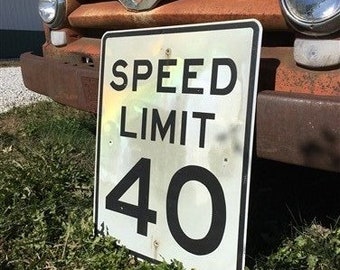 Peut inclure: Un panneau de limitation de vitesse blanc et noir avec le texte "SPEED LIMIT 40" sur un camion rouillé.