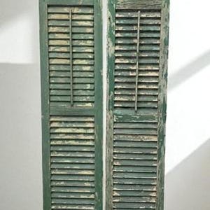 May include: Two weathered, green wooden shutters with horizontal slats and a central vertical support. The shutters show signs of age with peeling paint, suggesting a vintage or antique aesthetic. The shutters are displayed against a white background.