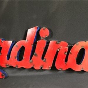 May include: Red metal sign with the word "Cardinals" in blue outlined letters. The sign has a distressed, vintage look.